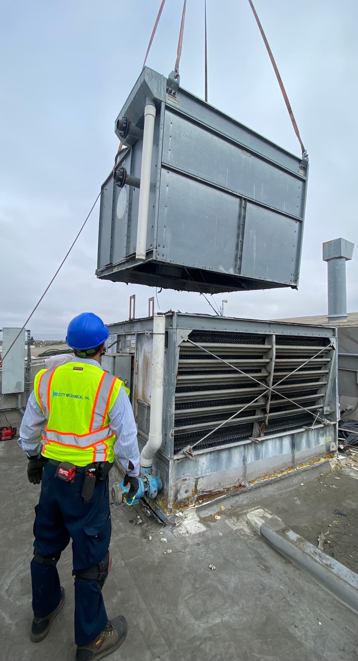 City Mechanical technician with CMI vest on a roof during a crane lift